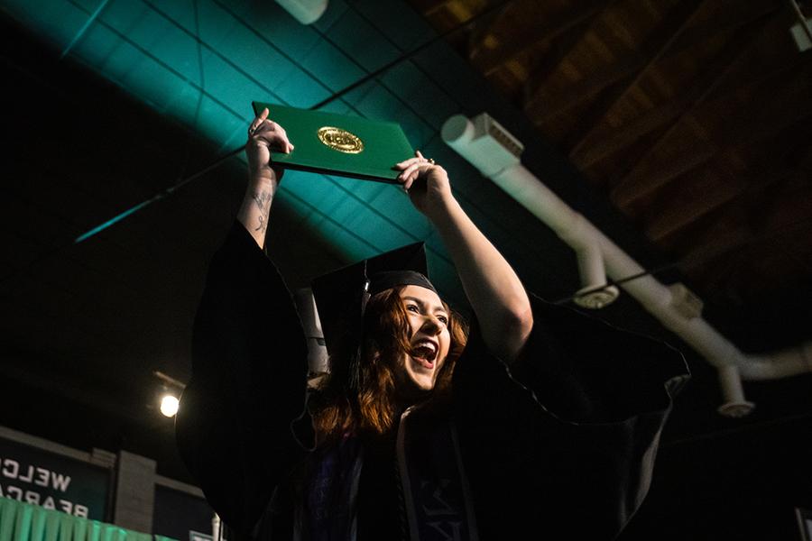 周六，<a href='http://zcggs.skygame168.net'>和记棋牌娱乐</a>的一名毕业生在毕业典礼上展示她的毕业证书.